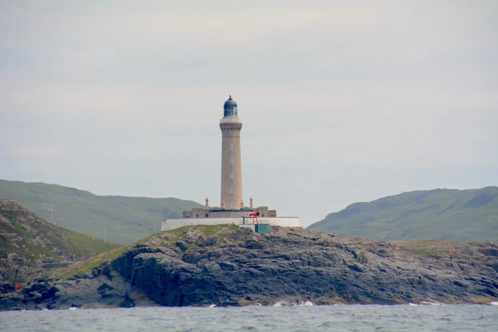 North Sea Challenge I steht auf einer felsigen Insel mit grünen Hügeln im Hintergrund.